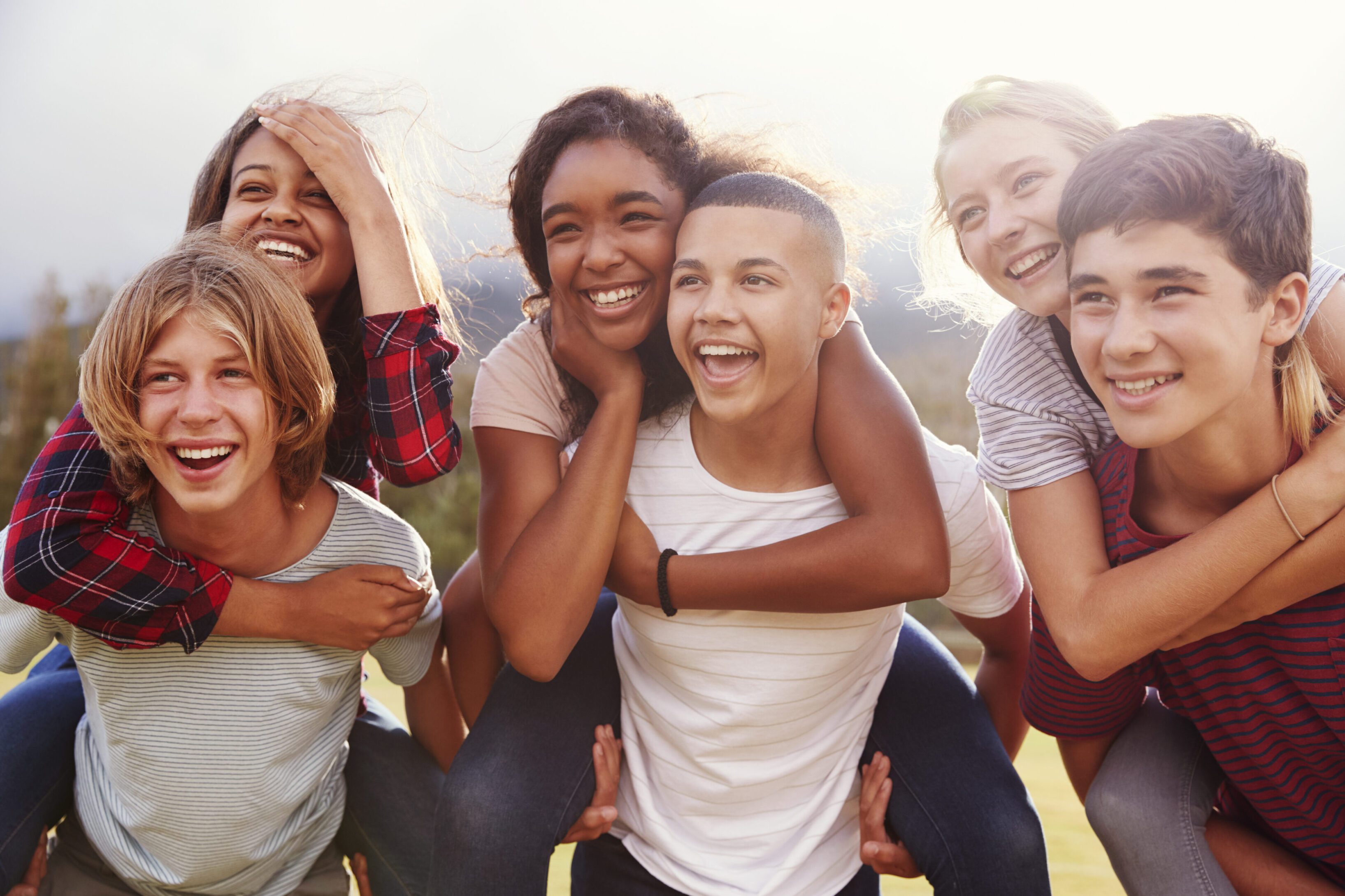 Teenage school friends having fun piggybacking outdoors Teenage school friends having fun piggybacking outdoors